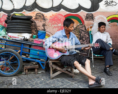 Ein Arbeiter, Gitarre zu spielen, auf der Straße in Phnom Penh, Kambodscha, Asien. Stockfoto