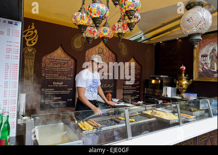 Ein Mann verkauft marokkanische Mahlzeiten in einem Stall in der Nähe des Rathauses in Wien, Österreich. Stockfoto