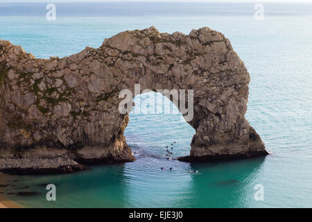 Das Meer Arch bei Durdle Door an der Jurassic Coast in Dorset auf einem ruhigen, sonnigen Tag. Schwimmer schwimmen durch den Torbogen. Stockfoto