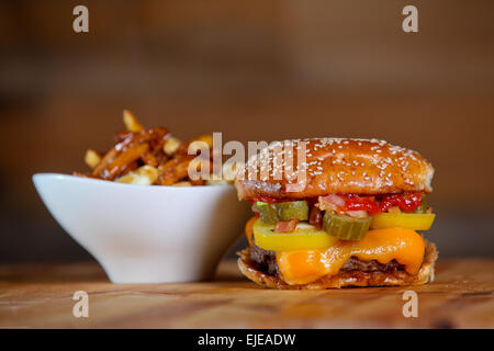 Bacon Cheeseburger mit Beilage Poutine Pommes Frites. Stockfoto