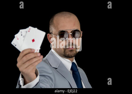 Mann im Anzug mit 4 Aces Poker Spielkarten in der Hand auf schwarzem Hintergrund isoliert Stockfoto