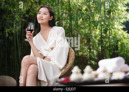 Die junge Frau trägt einen Bademantel in den roten Wein Stockfoto