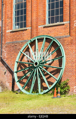 Eine große Kopfbedeckung Riemenscheibe für das Zechenhaus gewundenen Gang, lehnte sich gegen das Maschinenhaus Astley grünes Zeche-Museum. Stockfoto