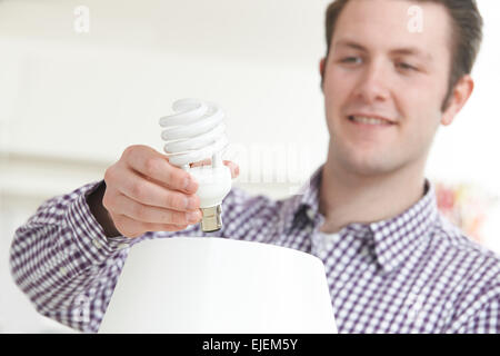 Mann, energiesparende Glühbirne in die Lampe zu Hause Stockfoto