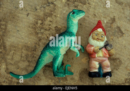 Spielzeug Modelle der großen Saurier oder Giganotosaurus und Gnome Geigenspiel auf gefärbten Karte liegen Stockfoto