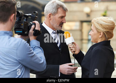 Journalistin mit Mikrofon interviewen Geschäftsmann Stockfoto