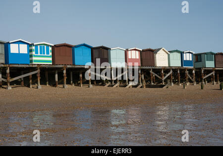 Eine Reihe von Strandhütten auf Stelzen gebaut, durch den Deich an Frinton-on-Sea, Essex. Auf der Rückseite haben sie einen kleinen offenen Bereich zum entspannen. Stockfoto