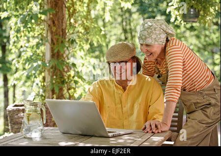 Älteres Paar im Freien mit einem Laptop, suchen sie am Computer. Möglicherweise haben Sie eine drahtlose video-Unterhaltung mit Enkelkindern. Stockfoto