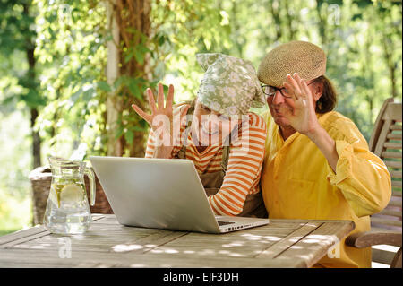 Älteres Paar im Freien mit einem Laptop, suchen sie am Computer. Möglicherweise haben Sie eine drahtlose video-Unterhaltung mit Enkelkindern. Stockfoto