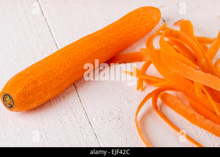 Frische geschälte Karotten in Scheiben geschnitten in dünne Stäbe für Karotten Julienne mit einem Cutter Metall Küche auf weißem Hintergrund Stockfoto