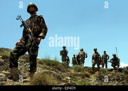 Ein afghanischer Soldat blickt auf eine als US-Soldaten und afghanische Grenzpolizisten sprechen Dorfältesten in Khas Kunar Bezirk der Kunar Provinz, Afghanistan, 1. Juli 2009. Die US-Soldaten sind bis zum 10. Gebirgs-Division der Firma A, 1. Bataillon, 32. Infanterie-Regiment zugewiesen.  US Armee Sgt. Matthew C. Moeller, 5. Mobile Public-Affairs-Abteilung Stockfoto