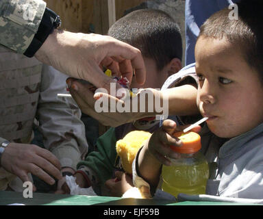 Eine afghanische Mutter erhält eine Handvoll Süßigkeiten von ein Soldat der US-Armee, als ihr Sohn es eng während der Operation sorgen bei der Elsalam ägyptischen Feldlazarett in der Nähe von Bagram Airfield, Afghanistan, 10. Mai 2007 die Augen.  Betrieb-Care ist eine freiwillige Organisation von Luftwaffe, Heer, Marine und Marine Servicemembers sowie US-Unternehmer, die Kleidung, Spielzeug und Schuhe für die Bedürftigen ausgezahlt.  Staff Sgt April Lapetoda Stockfoto