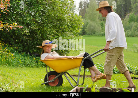 Ältere Mann trägt eine ältere Frau in einer Schubkarre. Sie lachen und Spaß haben. Stockfoto