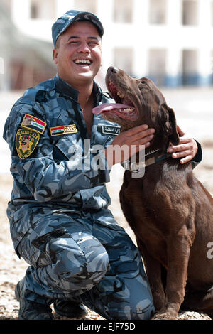 Ein Hundeführer mit der irakischen Polizei Al Anbar K-9 Unit in Ramadi, Irak, lobt seinen Hund, Sassy, ein chocolate Labrador Retriever, nachdem sie erfolgreich eine explosive Probe gefunden, während des Trainings, April 16.         Anbar Police aufstehen k-9 Unit /-news/2010/04/23/37917-anbar-police-stand-up-k-9-unit/index.html Stockfoto