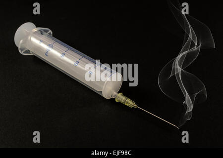 Eine komplette ungenutzte medizinische Spritze sitzt auf einem grauen Hintergrund Stockfoto