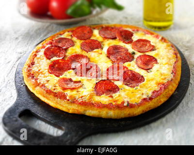 Pizza mit Salami & Käse mit einer Scheibe aus Stockfoto