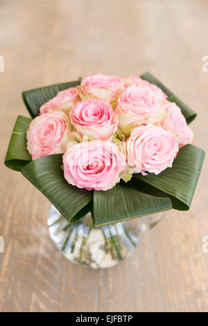 Vase mit Blumen - Spitzen-umrandeten Pastell rosa Rosen in einer eleganten Bouquet Stil Blumenarrangement mit Banane Blätter in Glaskanne Stockfoto