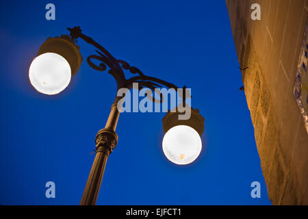 Alte Stadt-Straßenlaterne beleuchtet in der Abenddämmerung neben der Kathedrale Wand Stockfoto