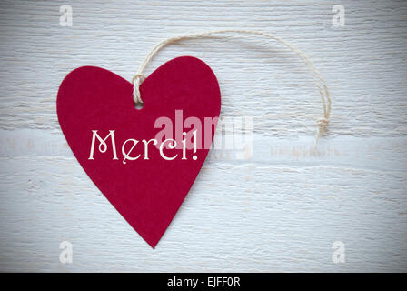 Ein rotes Herz Label oder Etikett mit weißen Band auf weißem Holz Hintergrund mit französischen Text Merci bedeutet glücklich danke Vintage Ret Stockfoto