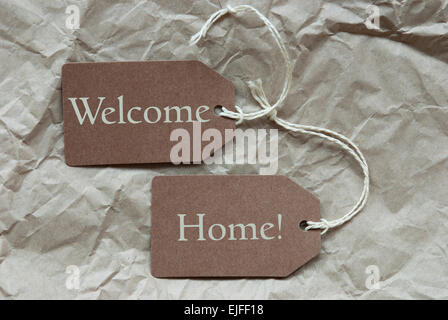 Zwei braune Etiketten oder Tags mit weißen Band auf zerknittertes Papierhintergrund mit Englisch Text Welcome Home Vintage oder Retro-Stil Stockfoto