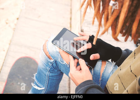 Abgeschnitten Bild männlichen Freiberufler mit Dreadlocks sitzen mit digital-Tablette eingeben selektiven Fokus warm Nachrichtenfilter angewendet Stockfoto