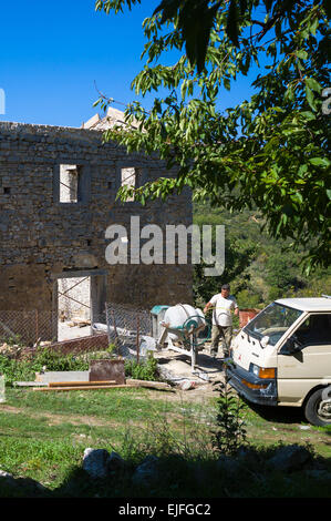 Arbeiten bei Betonmischer für Mauerwerk, die Wiederherstellung der verfallenen Haus in Trümmern in re-Entwicklung im Dorf, alte Perithia - Palea Baumeister Stockfoto