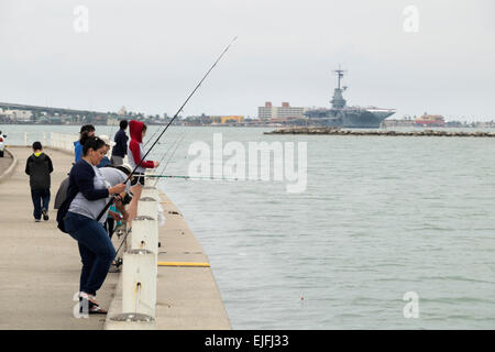 Hispanische Familie Angeln in Corpus Christi Bay mit der U.S.S. Lexington im Hintergrund. Stockfoto