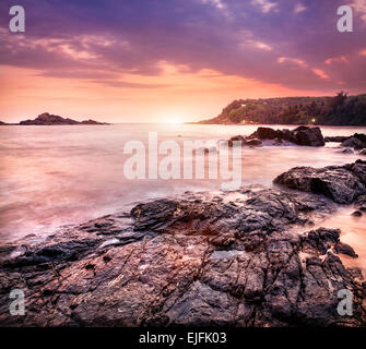 Meer mit Felsen an violetten Sonnenuntergang Himmel in Om Beach, Gokarna, Karnataka, Indien Stockfoto