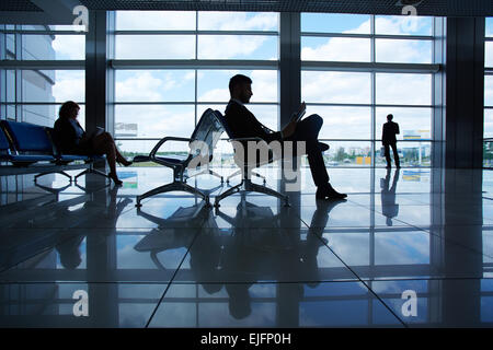 Gliederung der Geschäftsmann lesen während des Wartens auf Abfahrt in Flughafen Stockfoto