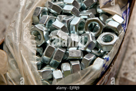 Plastikbeutel der Last der neuen Legierung Muttern über einen mechanischen Tisch Stockfoto