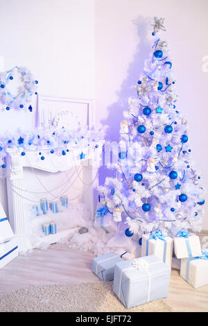 Weihnachtsbaum, Kamin, Uhren, Spielzeug, Geschenke in einem weißen Raum Stockfoto