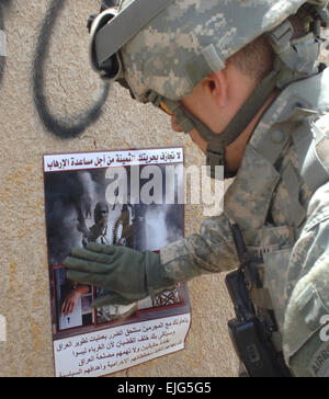 US Army Staff Sgt. Don Ingram legt ein Poster an der Wand während einer Patrouille im Bereich Furat von Bagdad, Irak, 8. Mai 2007. Das Poster enthält die Koalition Kraft Sicherheitsmitteilung und bittet die Bevölkerung um Hilfe bei der Ermittlung und Erfassung der Aufständischen. Ingram ist von der 318th psychologische Operations Company, 28. Infanterie-Regiment, 1. Bataillon, 1. US-Infanteriedivision, 4th Brigade Combat Team befestigt.   Staff Sgt Bronco Suzuki Stockfoto