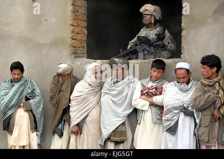 Ein Soldat der US-Armee bietet Sicherheit aus einem Gebäude, während andere Soldaten humanitären Hilfe für Menschen in Baraki Barak Bezirk Mitte in Baraki Barak in der Provinz Logar, Afghanistan, 5. April 2009 liefern. Die Soldaten der 10th Mountain Division 3rd Brigade Combat Team zugewiesen.    Nathaniel Allen SPC. Stockfoto