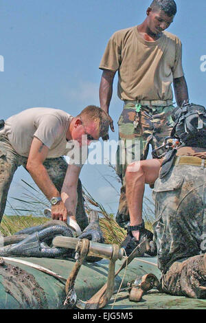 US Armee Sgt. Michael Linn, 1. Bataillon, 228th Aviation Regiment Black Hawk Crewchief, strafft man der Slingload Gurte am ein abgestürztes Flugzeug der Belize Defence Force BN-2 b Verteidiger in Belize 3. Mai 2007. Soldaten aus Joint Task Force-Bravo, mit Hilfe von Truppen aus Belize Defence Force, sind rigging der abgestürzten Verteidiger Flugzeug- und Slingloading es auf einer US-Armee UH-60 Black Hawk Hubschrauber für die Auslieferung an die BDF Air Station in Belize City International Airport.  Staff Sgt Chyenne A. Griffin veröffentlicht Stockfoto