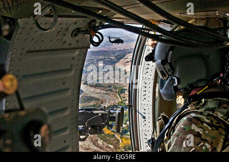 US Army Captain Tim Beecher mit der 82nd Combat Aviation Brigade, Task Force Talon mans seine Waffe an der Tür ein UH-60 Black Hawk als er und ein weiterer Black Hawk fliegen in der Nähe der Tora Bora entlang der pakistanischen Grenze 5 November Stockfoto