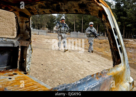 US-Armee Pfc. Carlos Ortiz, links, und Spc. Kevin Vo gehen vorbei an einem ausgebrannten Auto während einer Reise in ein Dorf in der Nähe von Shahr-e Safa, Afghanistan, 19. Januar 2011. Provinzielle Rekonstruktion-Mannschaft-Zubul besuchten das Dorf, um zukünftige Projekte zu bewerten und sprechen Sie mit älteren Fragen innerhalb des Dorfes.  Staff Sgt Brian Ferguson Stockfoto