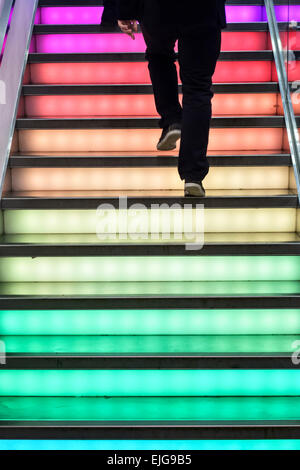 Ein Mann zu Fuß eine bunt beleuchtete Treppe an der Fashion-Store Uniqlo, Regent Street im Londoner West End Stockfoto