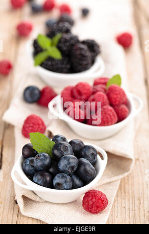 Heidelbeeren, Brombeeren und Himbeeren in kleinen weißen Schalen. Stockfoto