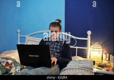 Eine Teenager-Mädchen nutzt ihr Laptop in ihrem Schlafzimmer. MODEL RELEASED Stockfoto