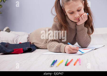 kleines Mädchen auf dem Boden auf ihrem Notebook mit Filzstiften ausmalen Stockfoto