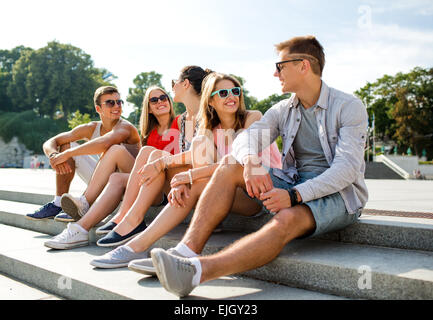 Gruppe von lächelnden Freunde sitzen auf Stadtstraße Stockfoto