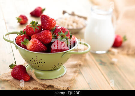 Frische Erdbeeren in Sieb auf Holztisch. Stockfoto