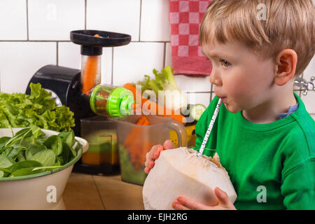 Niedlichen Kleinkind jungen Kokosnuss Trinkwasser in der Küche. Stockfoto