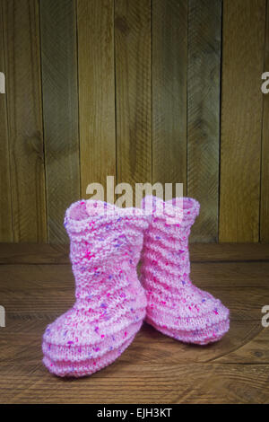 Rosa gestrickte Baby Socken auf dem Hintergrund der Holzbretter Stockfoto