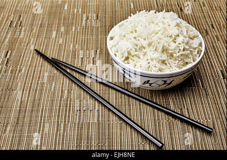 Bio gekocht Jasmin Reis ungeschält in Oriental Schale und Stäbchen auf tropischen Stil Gedeck Stockfoto
