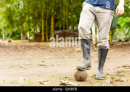 Fußball-Thema mit Gummistiefeln und Alter Ball im ecuadorianischen Dschungel Stockfoto