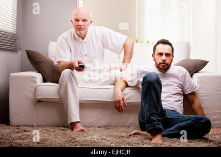 ein paar Freunde Sportübertragungen im Fernsehen in einem weißen Wohnzimmer auf dem sofa Stockfoto