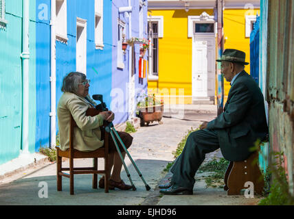 Älterer Mann und Frau sitzen in der Straße vor bunten Hintergrund, Valparaiso, Chile Stockfoto