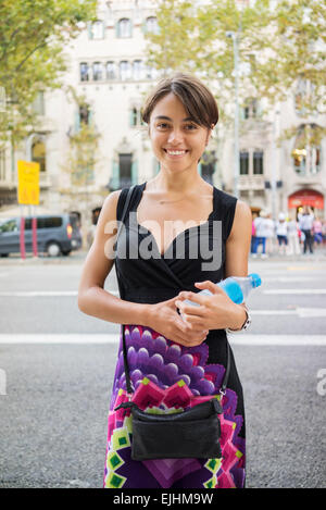 Schöne junge Mädchen lächelnd, hält eine Flasche Wasser im Stadtraum Stockfoto