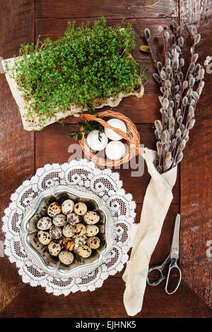 Ostern-Zusammensetzung von Willow Zweige mit Kätzchen, Kresse, Wachteleier in Metall Schale und Ostern Korb mit Eiern, eingestellt auf alten hölzernen Stockfoto